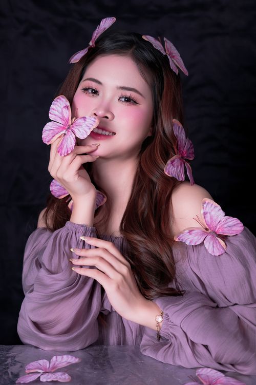 Free A beautiful woman adorned with pink butterflies, showcasing elegance and grace. Stock Photo