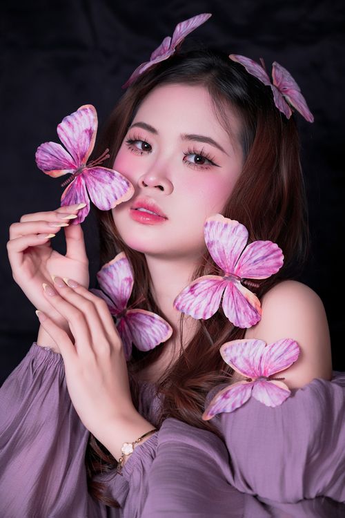 Free Elegant portrait of a woman adorned with pink butterfly accessories, creating a whimsical and dreamy ambiance. Stock Photo