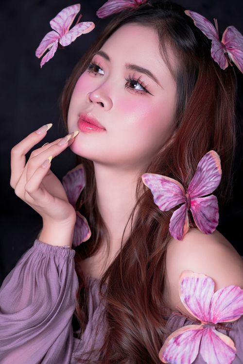 Free Artistic portrait of a young woman surrounded by pink butterflies, symbolizing beauty and grace. Stock Photo