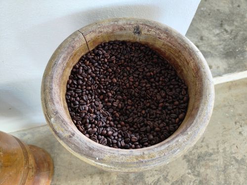 Free A wooden bowl overflowing with fresh coffee beans on a rustic surface. Stock Photo