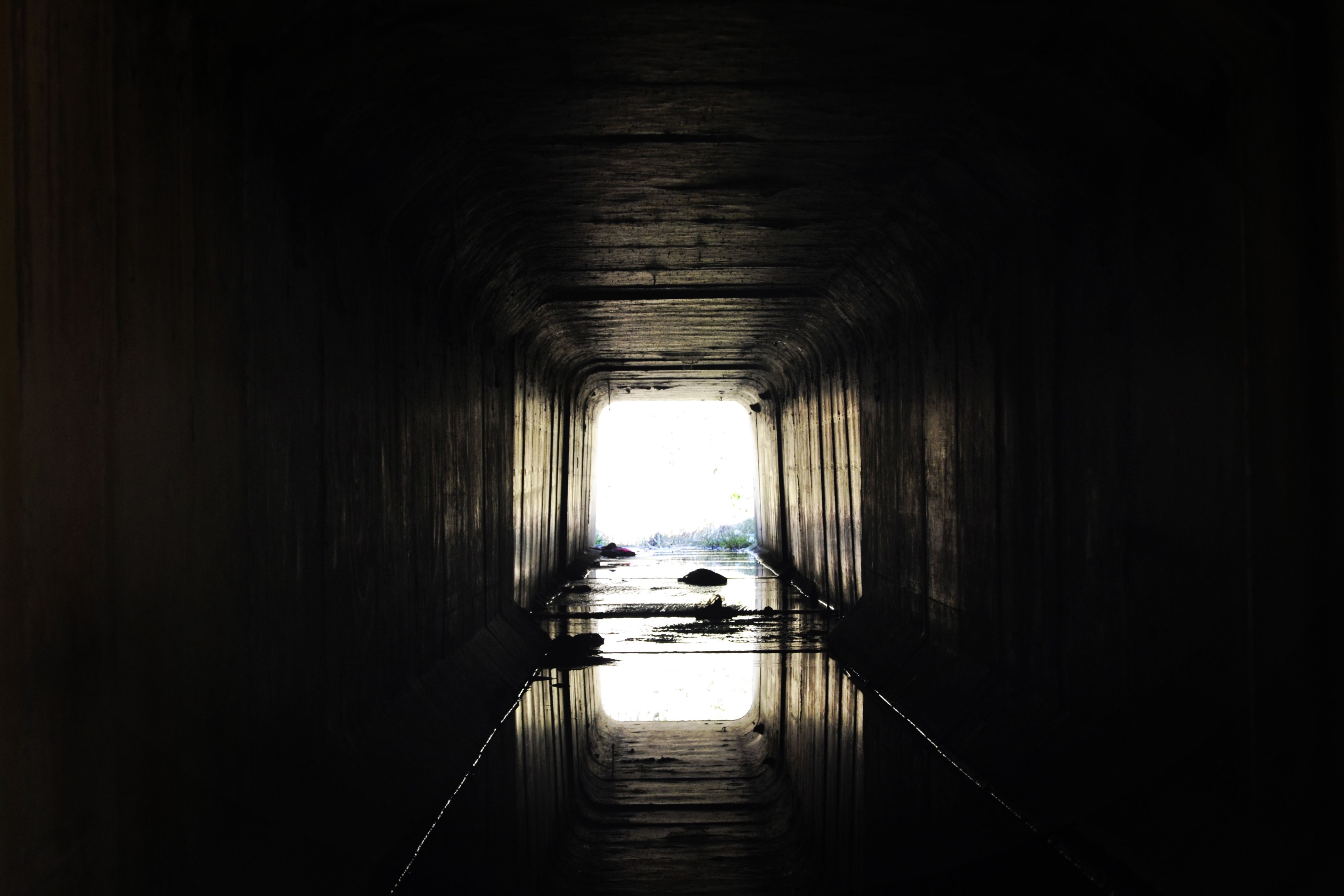A dark tunnel leading to a bright light, creating a moody and dramatic silhouette.