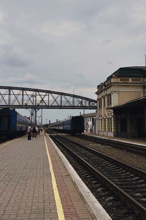 Free A railway station with idle trains under a cloudy sky, featuring a pedestrian overpass. Stock Photo