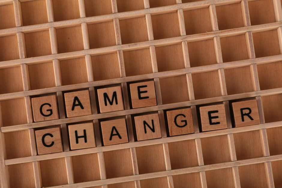 Scrabble tiles forming 'Game Changer' on a wooden grid, symbolizing innovation or transformation.