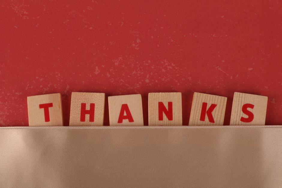 Wooden tiles with red letters spell 'Thanks', set against a red backdrop with a beige strip.
