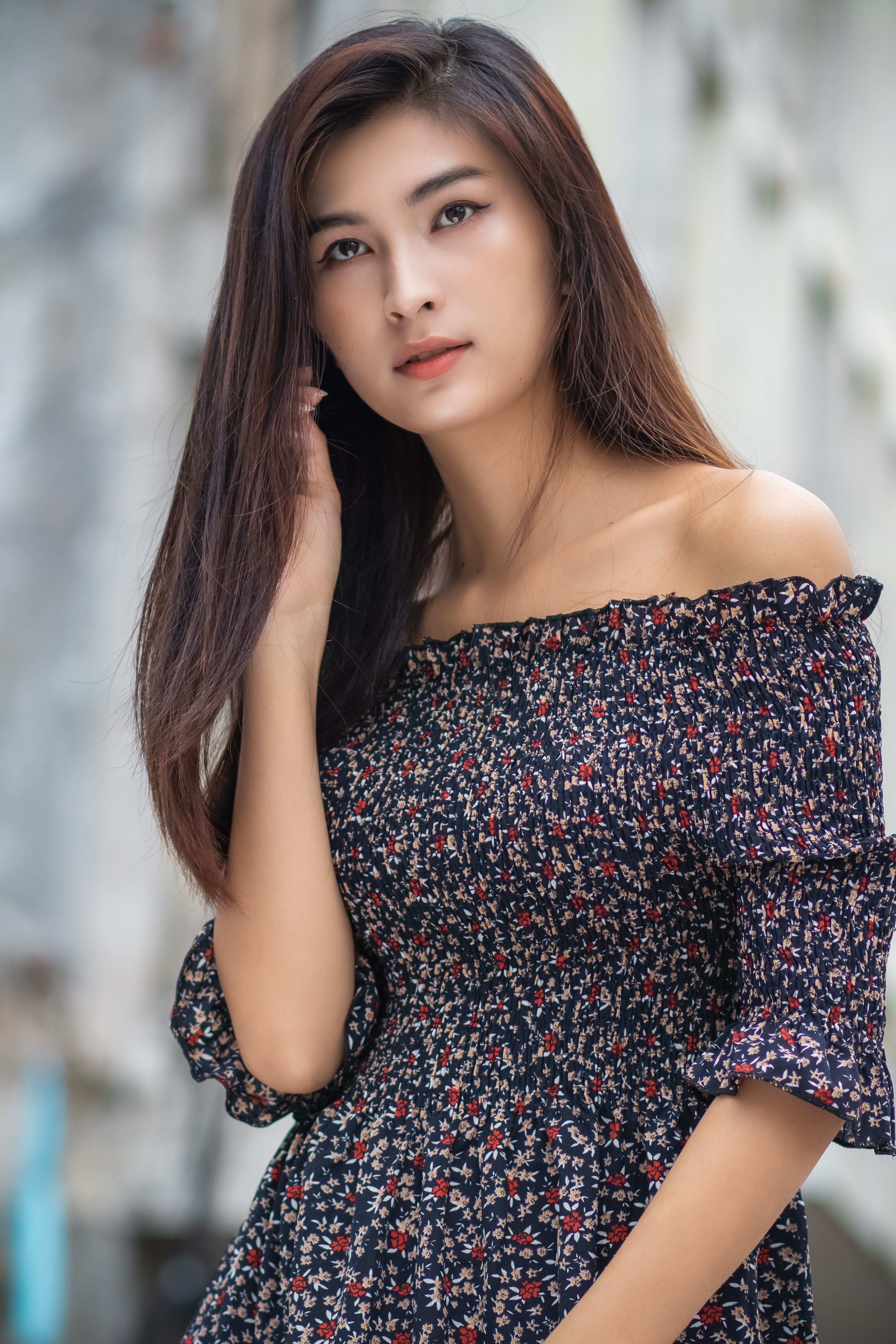 Captivating portrait of a beautiful young woman in a floral dress, radiating elegance and contemplation.