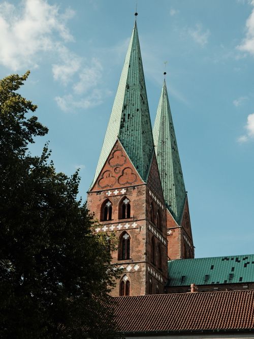 Free Historic Gothic church towers with teal roofs under a clear blue sky in Lübeck, Germany. Stock Photo