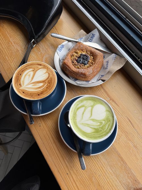 Free Stylish cafe tabletop with lattes and pastry by the window, rich in texture and flavor. Stock Photo