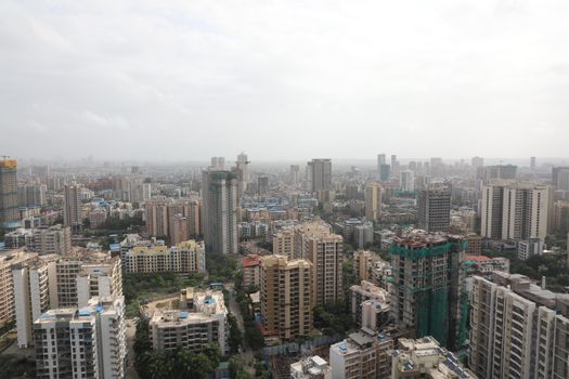 Overhead view of a bustling cityscape with high-rise buildings under a cloudy sky.