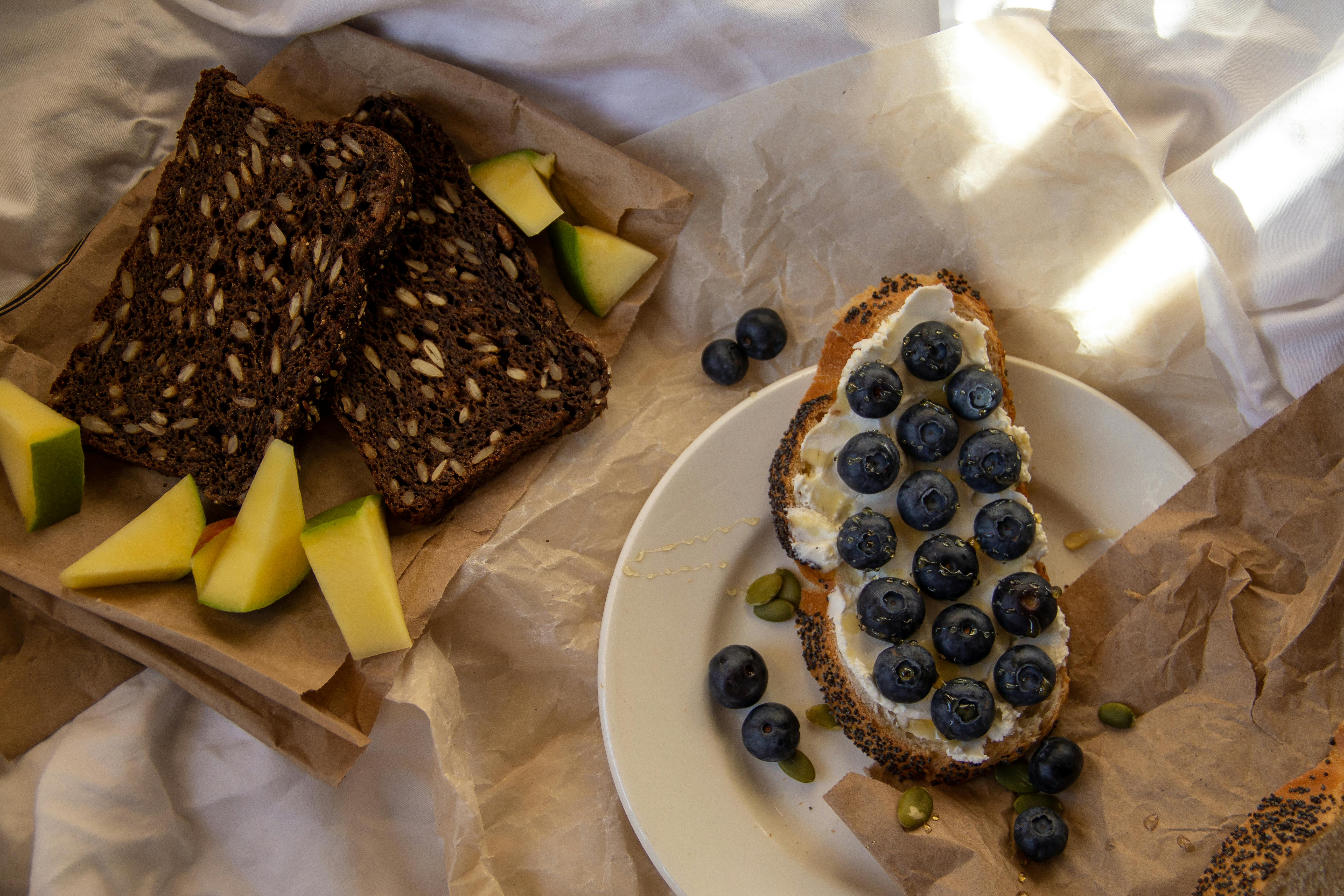 Delicious breakfast featuring blueberry-studded toast and slices of hearty rye bread with fruit.