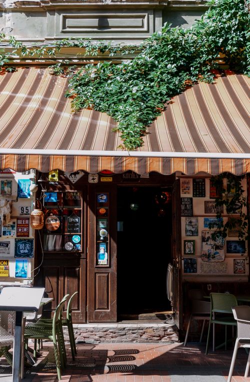 Free Cozy café entrance with vintage decor and lush greenery in Lviv, Ukraine's historic center. Stock Photo