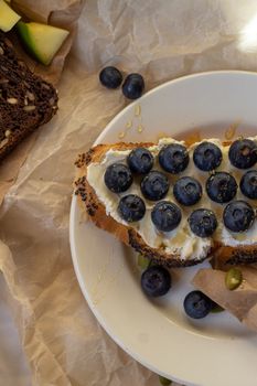 Savory toast topped with fresh blueberries, cream cheese, and seeds for a healthy breakfast option.