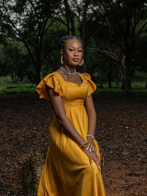 Free Portrait of a woman wearing a yellow gown in a serene forest environment, exuding elegance and tranquility. Stock Photo