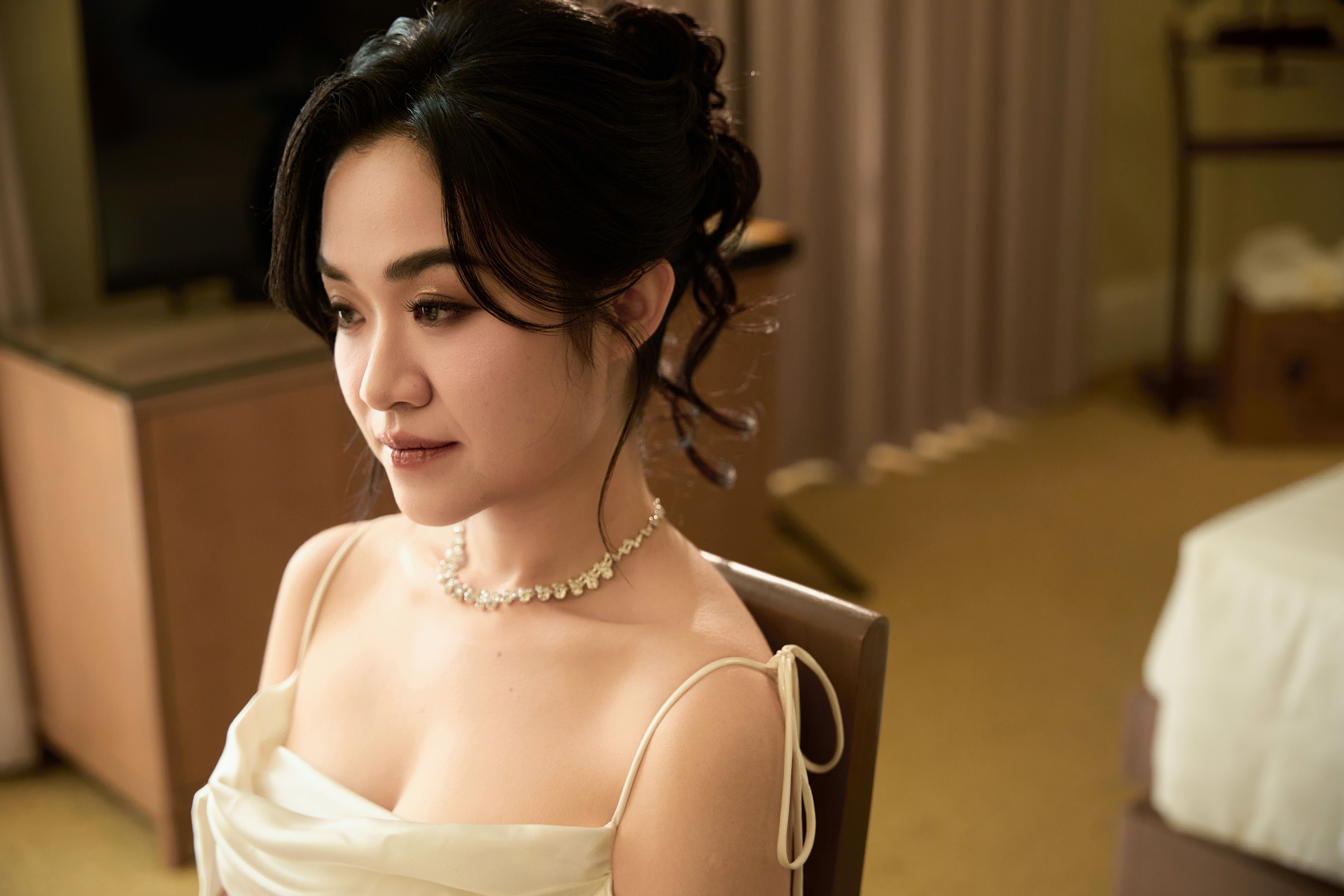 Portrait of an elegant woman in bridal attire with a necklace, captured indoors.