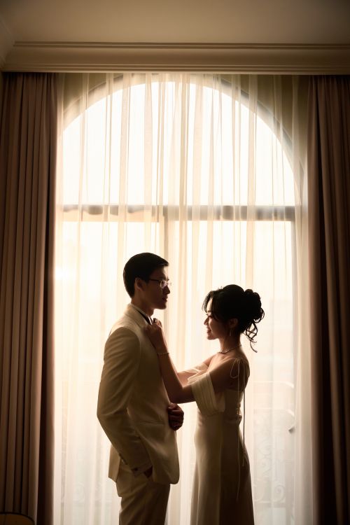 Free Silhouetted couple sharing an intimate moment by a curtained window. Stock Photo