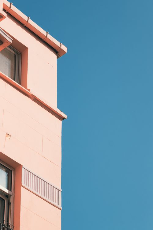 Free A modern pink building facade contrasts against a vibrant blue sky, epitomizing minimalist architecture. Stock Photo