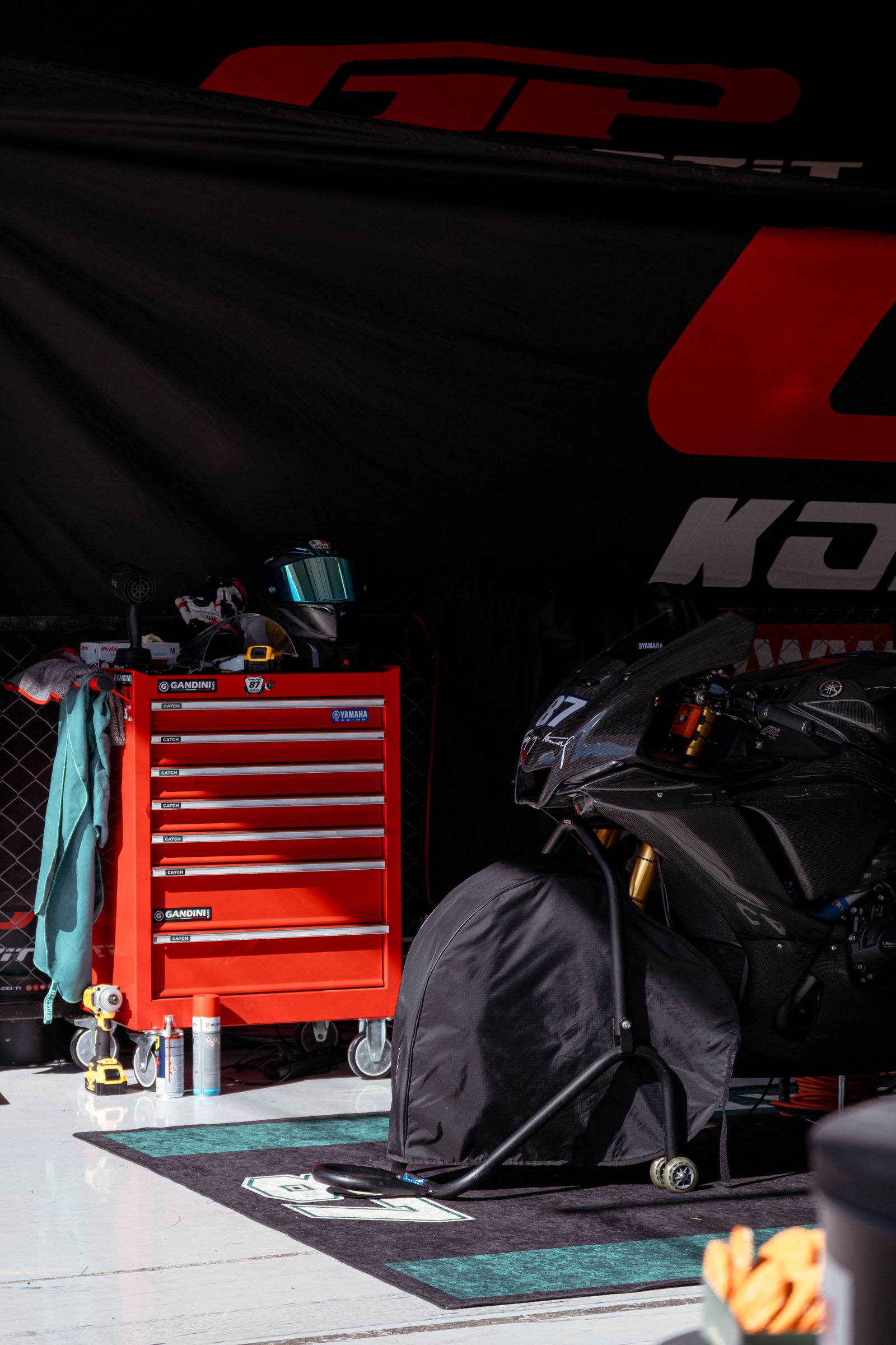 Coffre à outils rouge et moto sous housse dans un atelier automobile