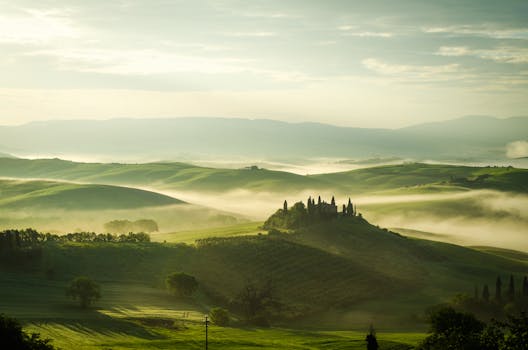 Breathtaking view of the Tuscany countryside with morning fog and rolling hills.