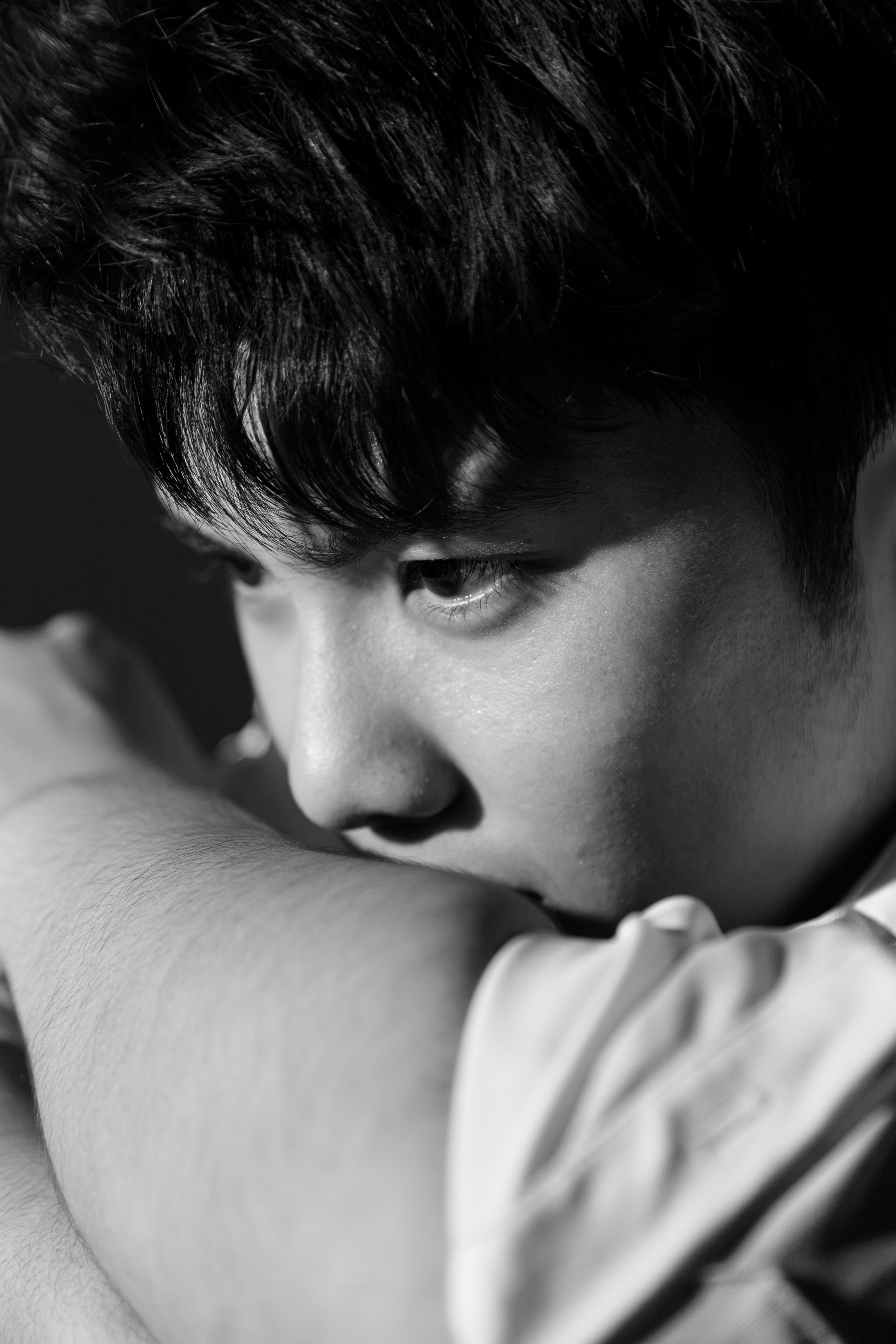Black and white portrait of a young man in reflective pose.