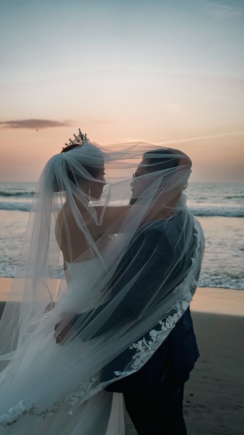 Free A couple embraces on the beach at sunset during their wedding ceremony. Stock Photo