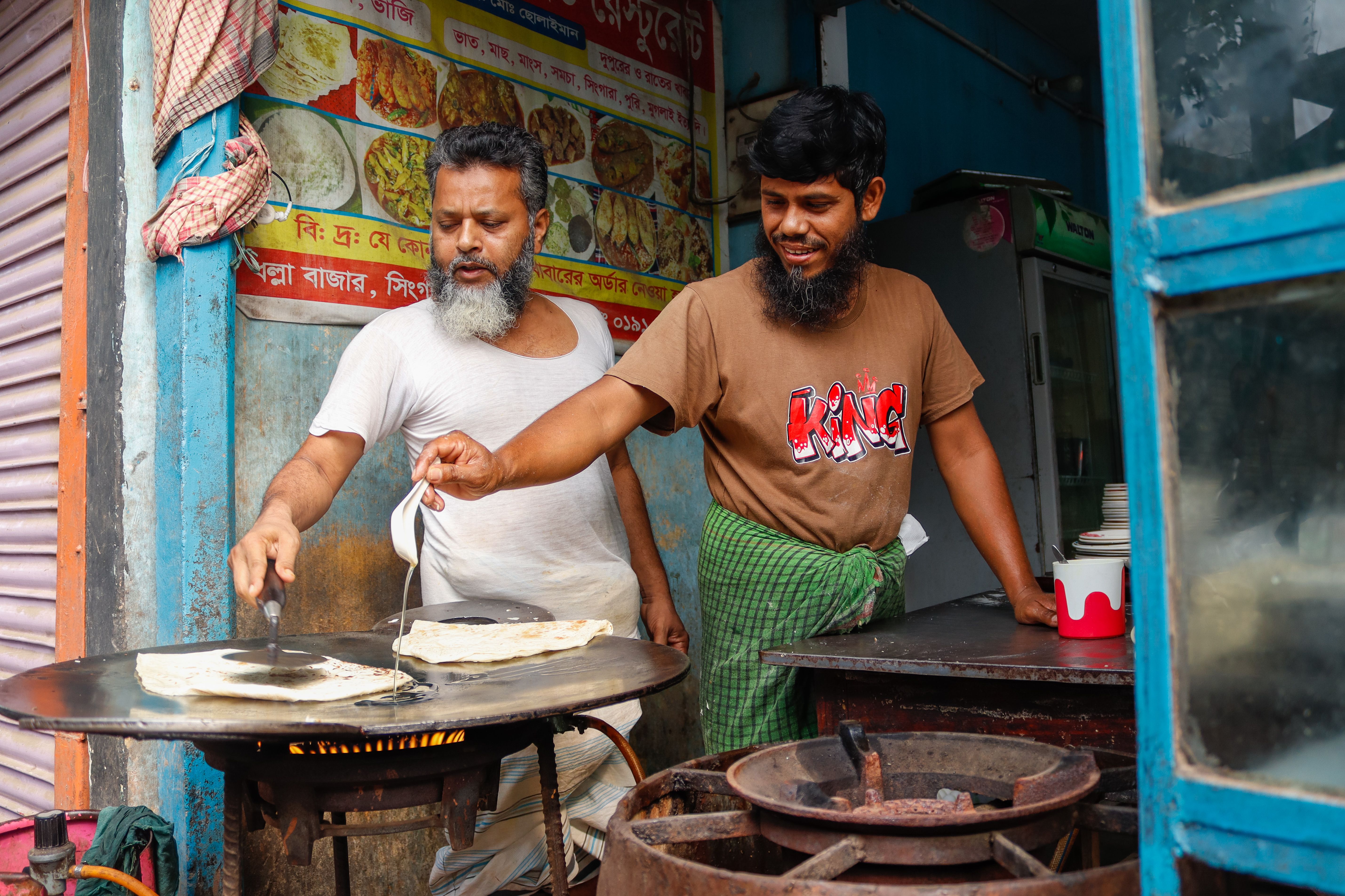 Cooks making roti on a large flat griddle — the griddle base and its motor housing are a common cockroach harbourage