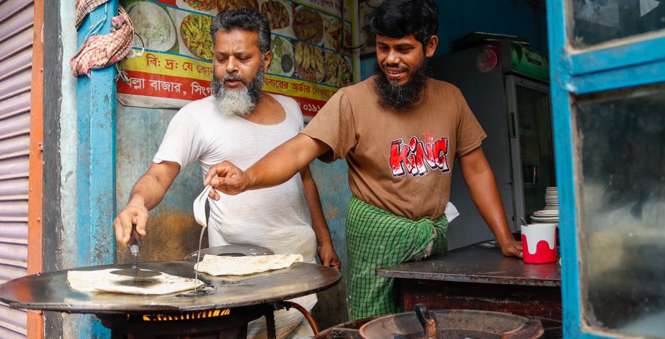 Cooks making roti on a large flat griddle — the griddle base and its motor housing are a common cockroach harbourage