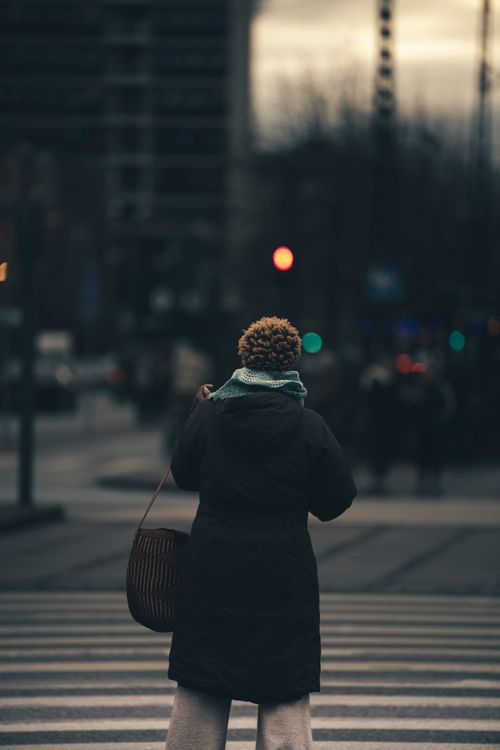 Free Person standing at a crosswalk in Copenhagen during twilight, capturing urban life. Stock Photo
