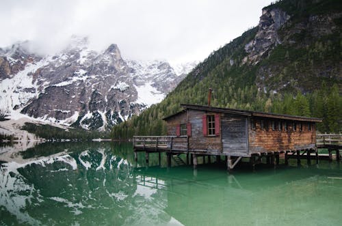 Casa De Madeira Marrom O Lake Perto De Montanha Coberta De Neve