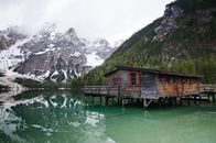 宁静的布雷斯湖上，乡村船库、白雪皑皑的山脉和郁郁葱葱的森林倒映其中