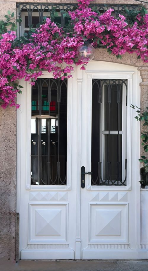 Free Beautiful white door adorned with vibrant bougainvillea flowers in Balıkesir, Türkiye. Stock Photo