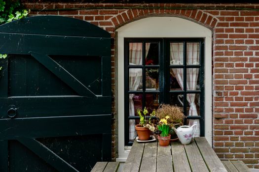 Charming brick wall with a window and potted plants, exuding rustic charm and cozy vibes.