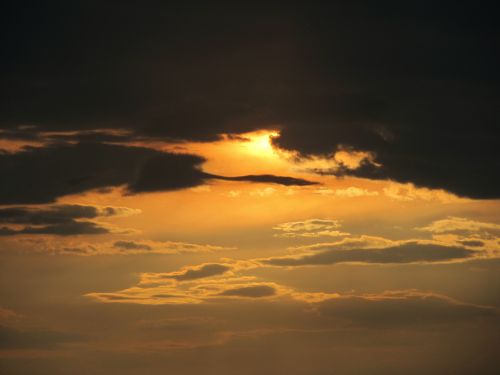 Free Capture of a stunning sunset with dramatic clouds and warm golden hues in the sky. Stock Photo