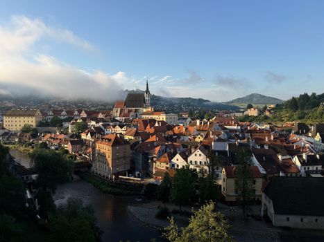 A picturesque view of Český Krumlov, Czech Republic, with its iconic red rooftops and historic architecture bathed in morning light.