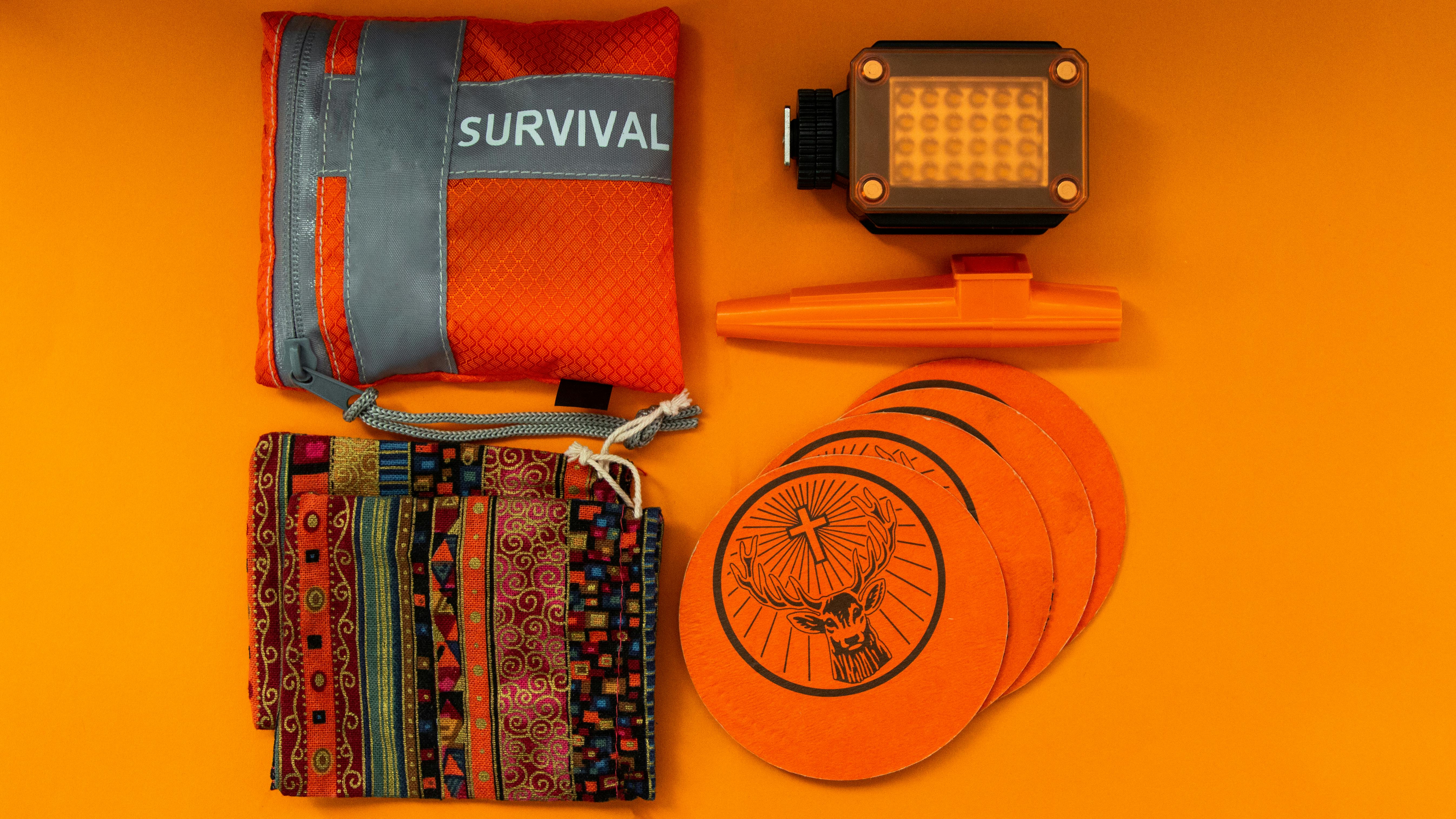 Flat lay of colorful survival kit items on orange background, showcasing vibrant essentials.