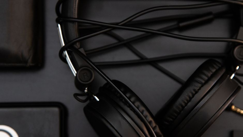 Black headphones and wallet on a dark surface, highlighting modern technology.