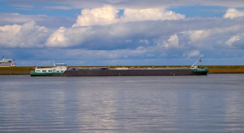 Free A large cargo barge sailing on a calm river under a picturesque cloudy sky. Stock Photo