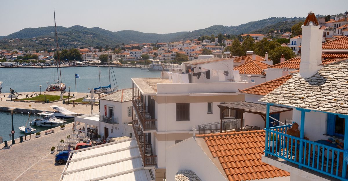 person journaling on a balcony overlooking a Mediterranean town at sunrise