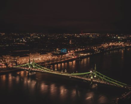 Aerial shot of the illuminated Liberty Bridge over the Danube River at night in Budapest, Hungary.
