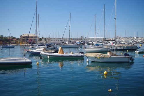 Free A serene scene of sailing boats docked at a marina in Malta under a clear blue sky. Stock Photo