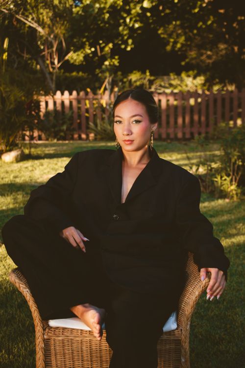 Free Elegant woman in black suit sitting outdoors in warm evening light, capturing style and tranquility. Stock Photo