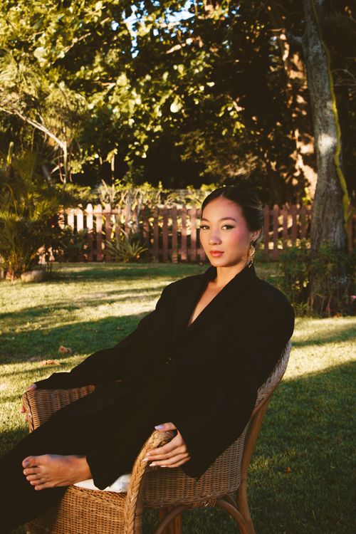 Free A stylish woman sitting in a garden, exuding tranquility and grace. Stock Photo