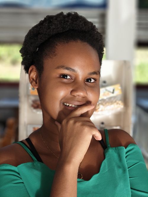 Free Portrait of a smiling young woman in a green top indoors, exuding warmth and confidence. Stock Photo