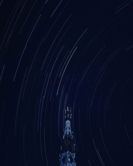 Long exposure captures dramatic star trails above a tower in the night sky. Long exposure captures dramatic star trails above a tower in the night sky.