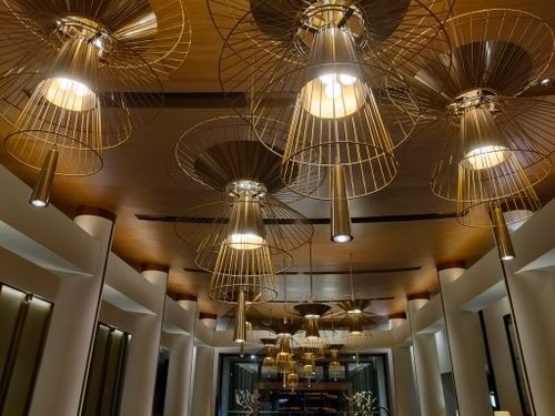 Free Luxurious modern ceiling lamps with golden wireframe design in a stylish hotel lobby, creating a warm ambiance. Stock Photo