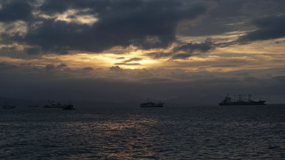Serene sunset with ships silhouetted against the cloudy sky over Solomon Islands.