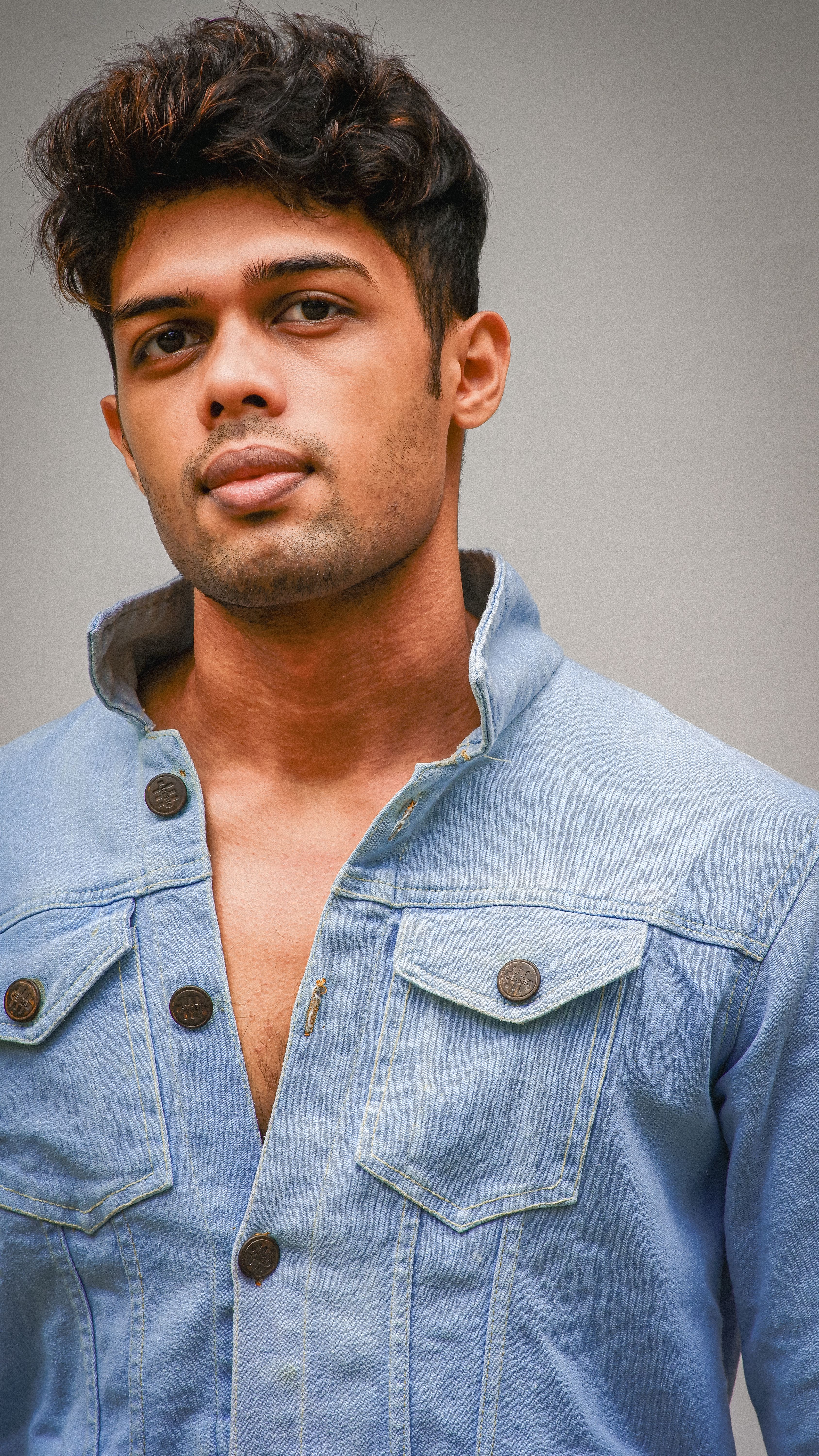 Portrait of a young man wearing a stylish denim jacket, looking confidently at the camera.