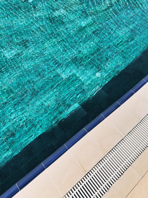 Free Close-up of turquoise pool water with tiled deck, perfect for summer and vacation themes. Stock Photo