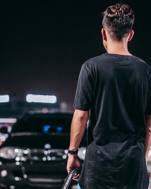 Man in Black Crew Neck T-shirt and Black Pants Standing on Parking Lot