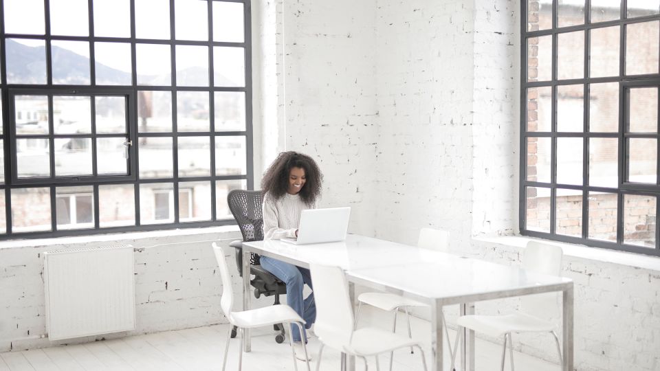 Mulher usando notebook em um ambiente de trabalho iluminado.