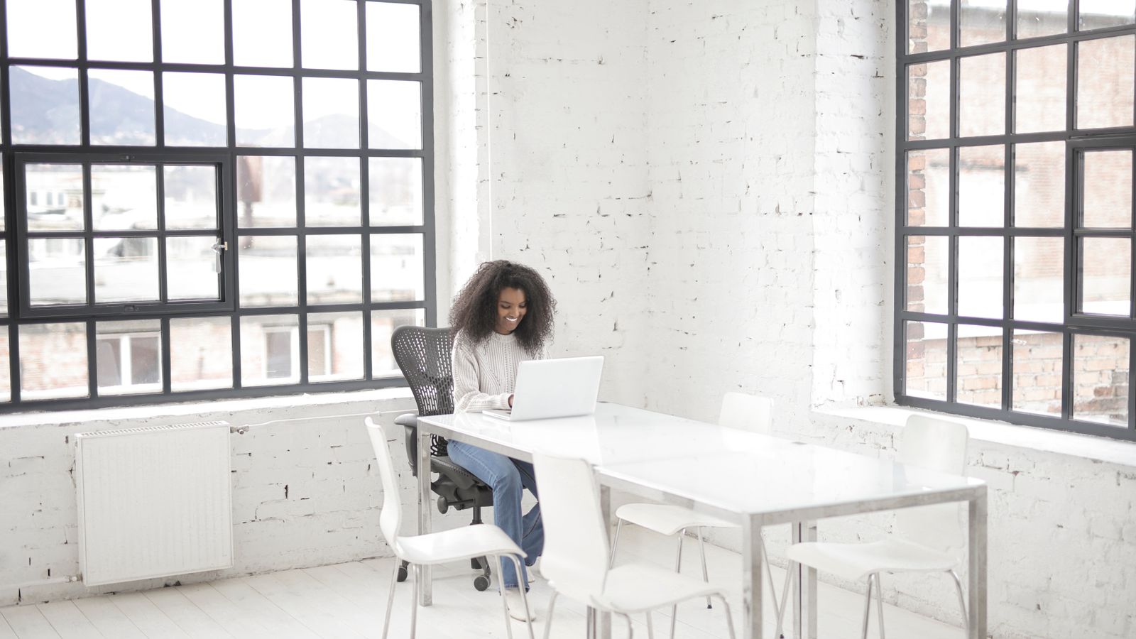 A woman working on a laptop in a bright modern workspace with natural light