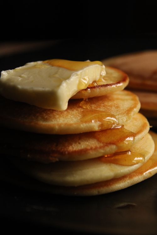 Free Close-up of a stack of pancakes topped with melting butter and syrup on a dark background. Stock Photo